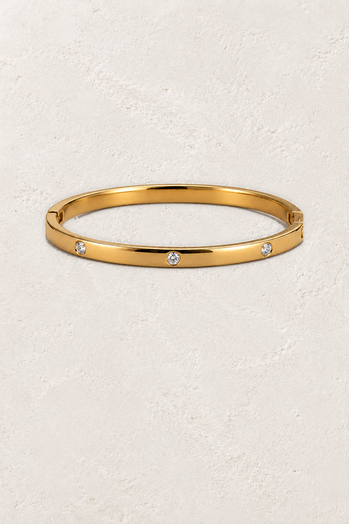 Amelie Gold Crystal Station Bangle on the reference plaster background