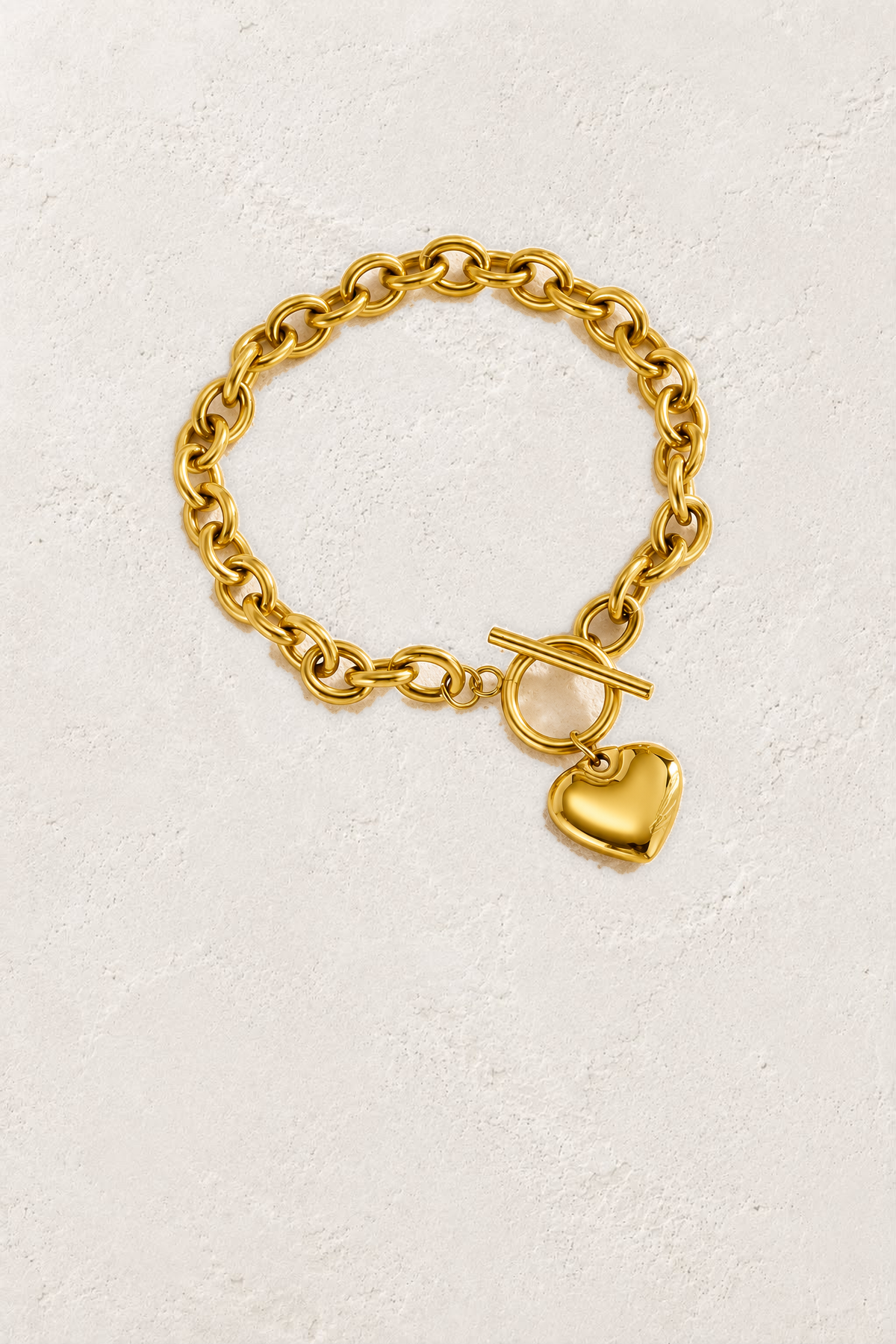 
                  
                    Amora Gold Heart Toggle Bracelet on the reference plaster background
                  
                