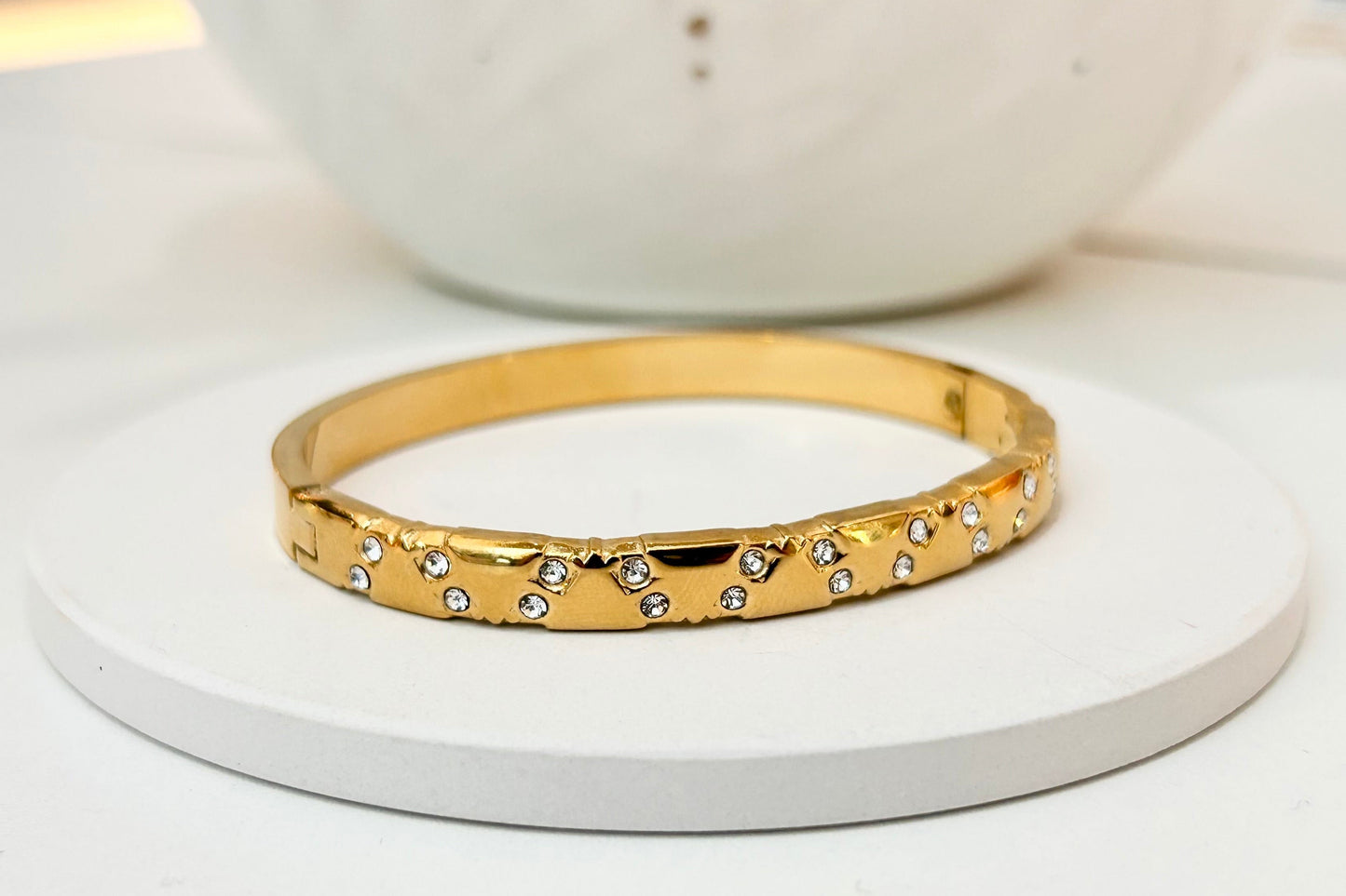 
                  
                    Stellara Textured Gold Scattered Crystal Bangle displayed on a white stand
                  
                