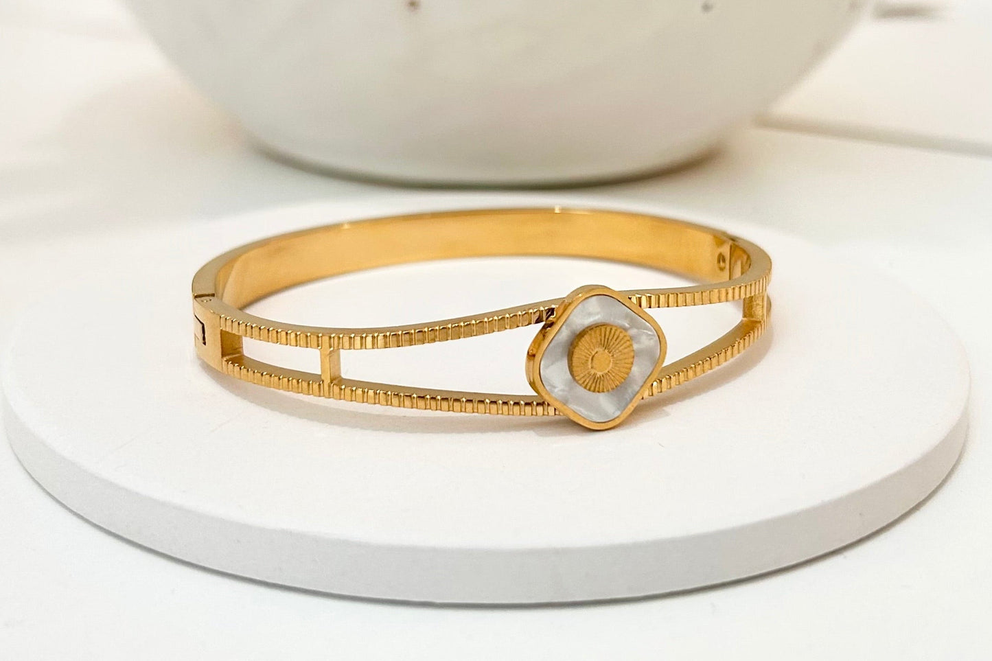 
                  
                    Lunaria Mother of Pearl Gold Bangle displayed on a white stand
                  
                