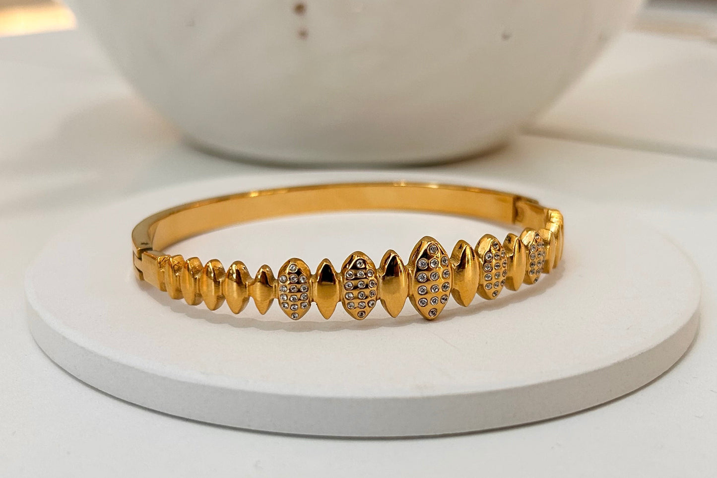 
                  
                    Solvaya Sculpted Gold Crystal Bangle displayed on a white stand
                  
                