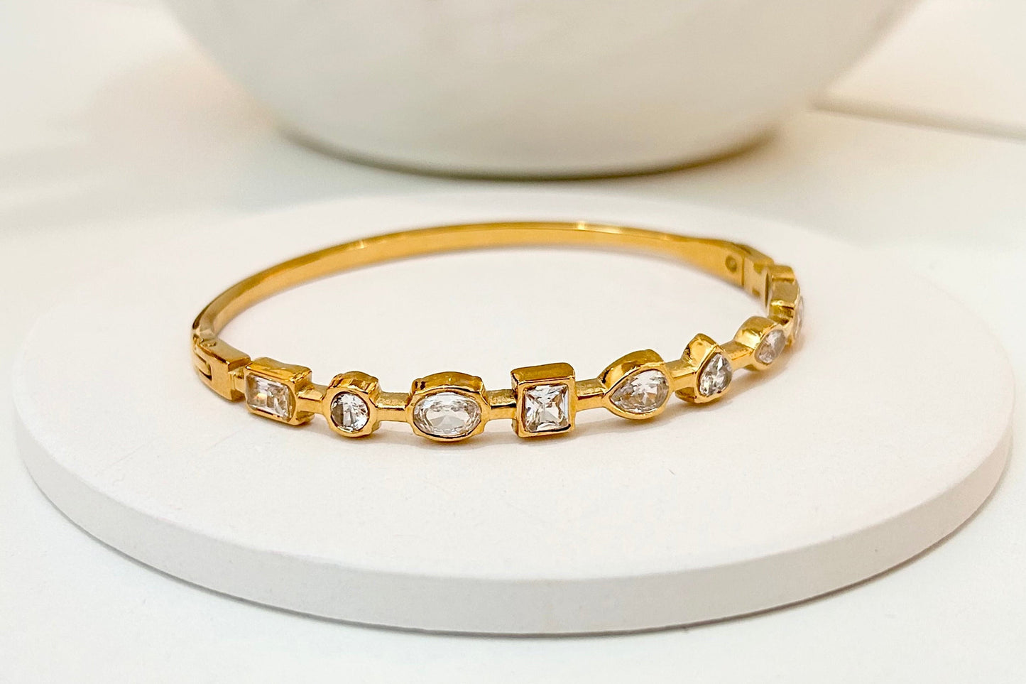 
                  
                    Aviora Gold Mixed-Cut Crystal Bangle displayed on a white stand
                  
                