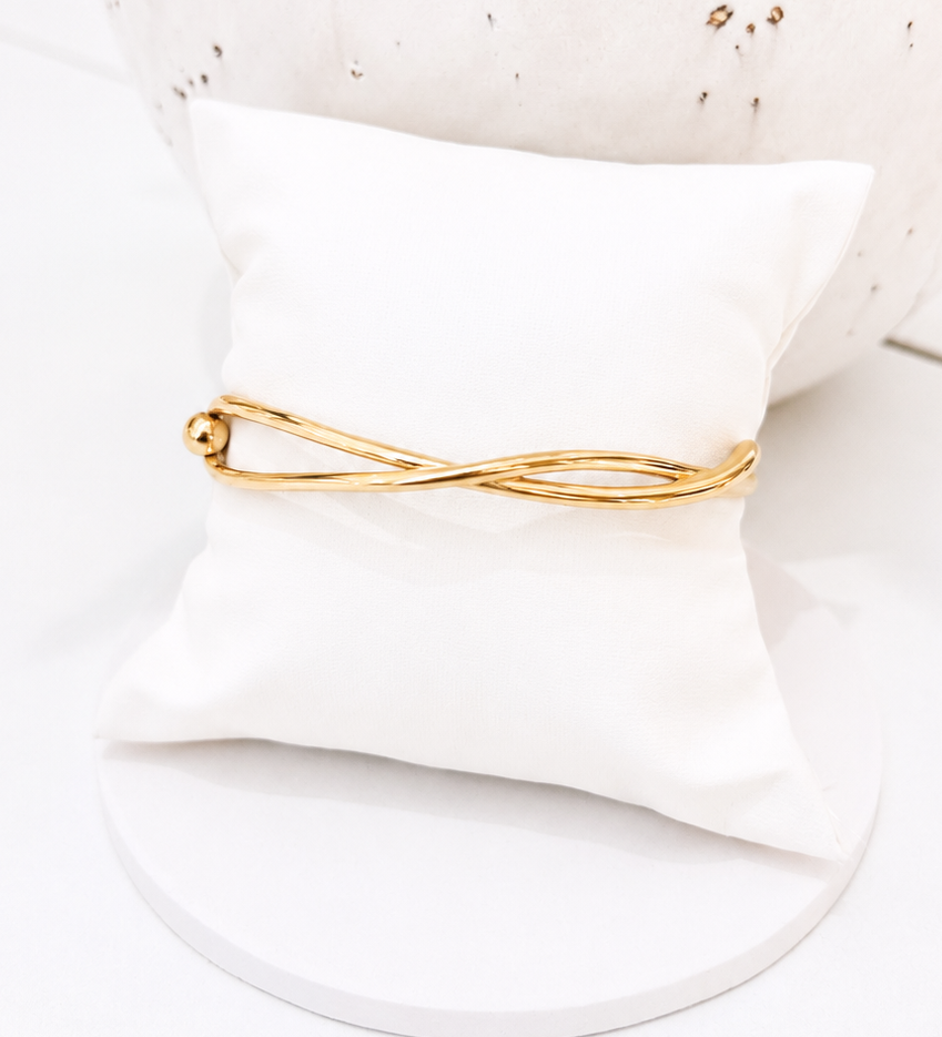 
                  
                    Élanora Gold Intertwined Open Bangle displayed on a white stand
                  
                