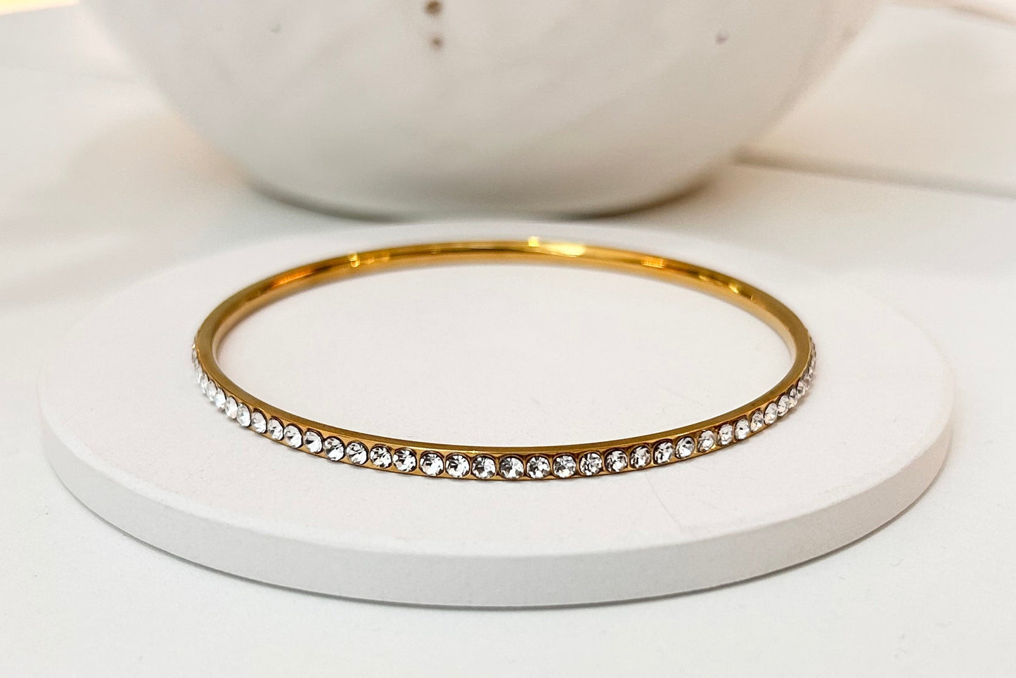 
                  
                    Elara Gold Tennis Bangle displayed on a white stand
                  
                