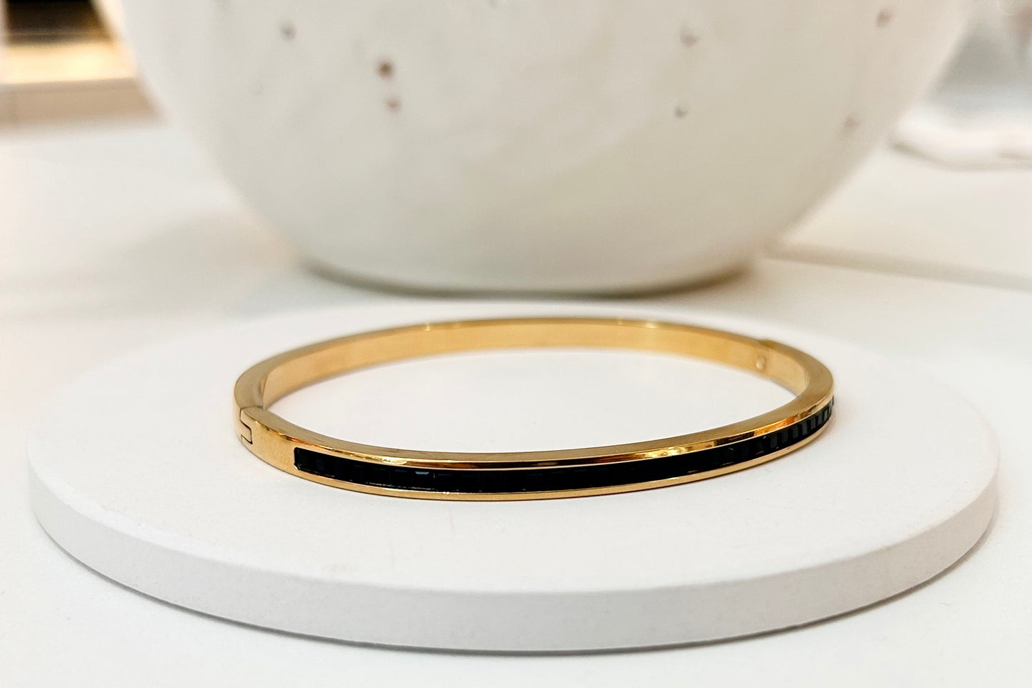 
                  
                    Noiré Black Crystal Gold Bangle displayed on a white stand
                  
                