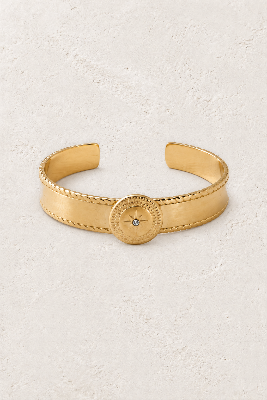 Asterelle Brushed Gold Sun Medallion Cuff on warm ivory plaster