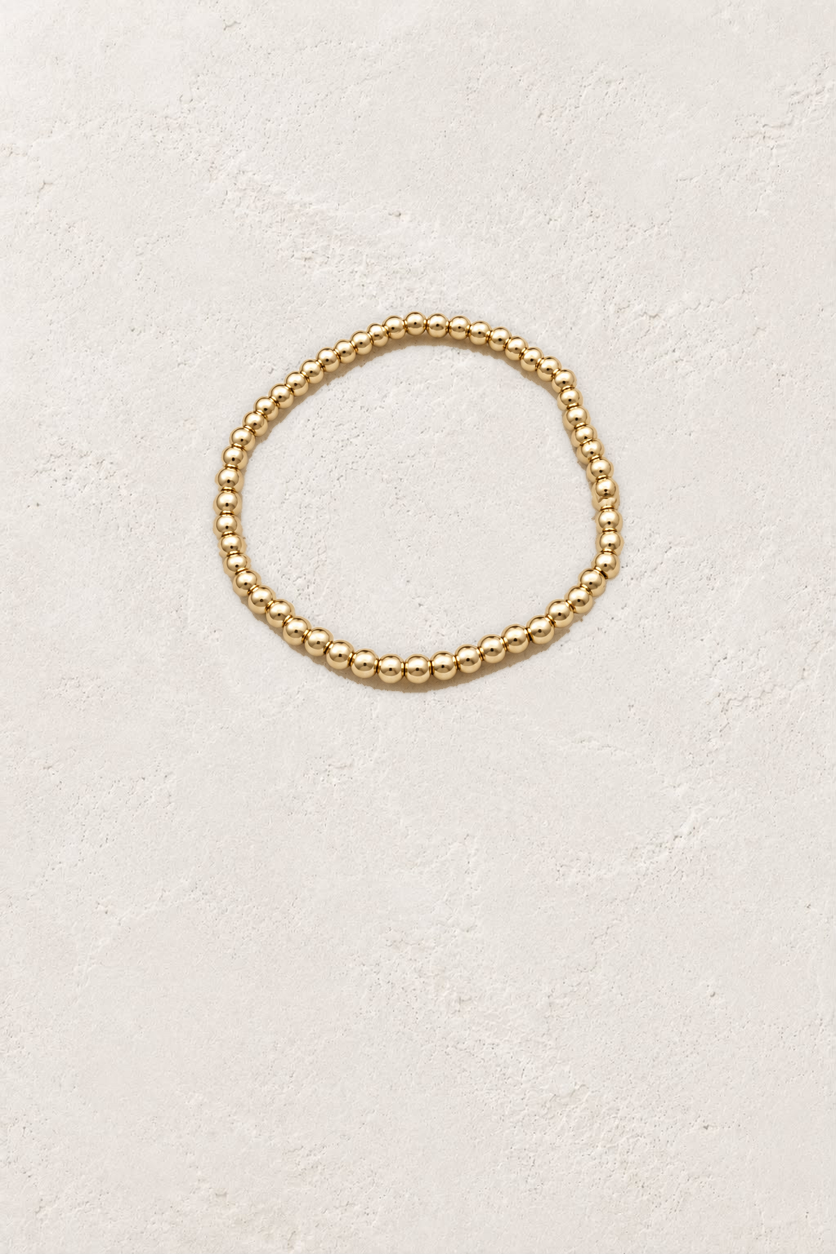 4mm Gold Plated Beaded Elastic Bracelet TF on the reference plaster background