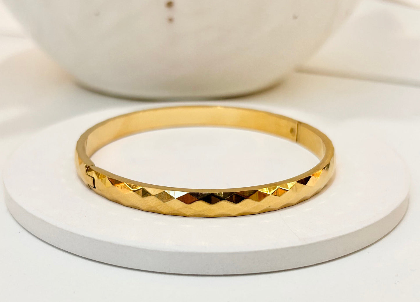 
                  
                    Valora Faceted Gold Bangle displayed on a white stand
                  
                