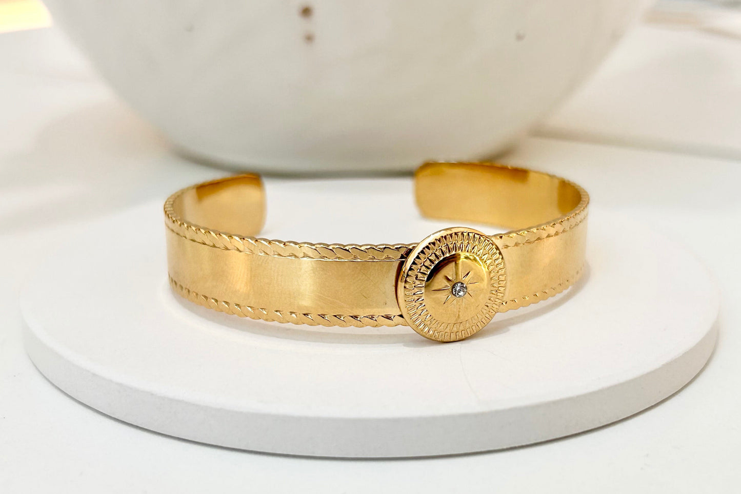 
                  
                    Asterelle Brushed Gold Sun Medallion Cuff displayed on a white stand
                  
                