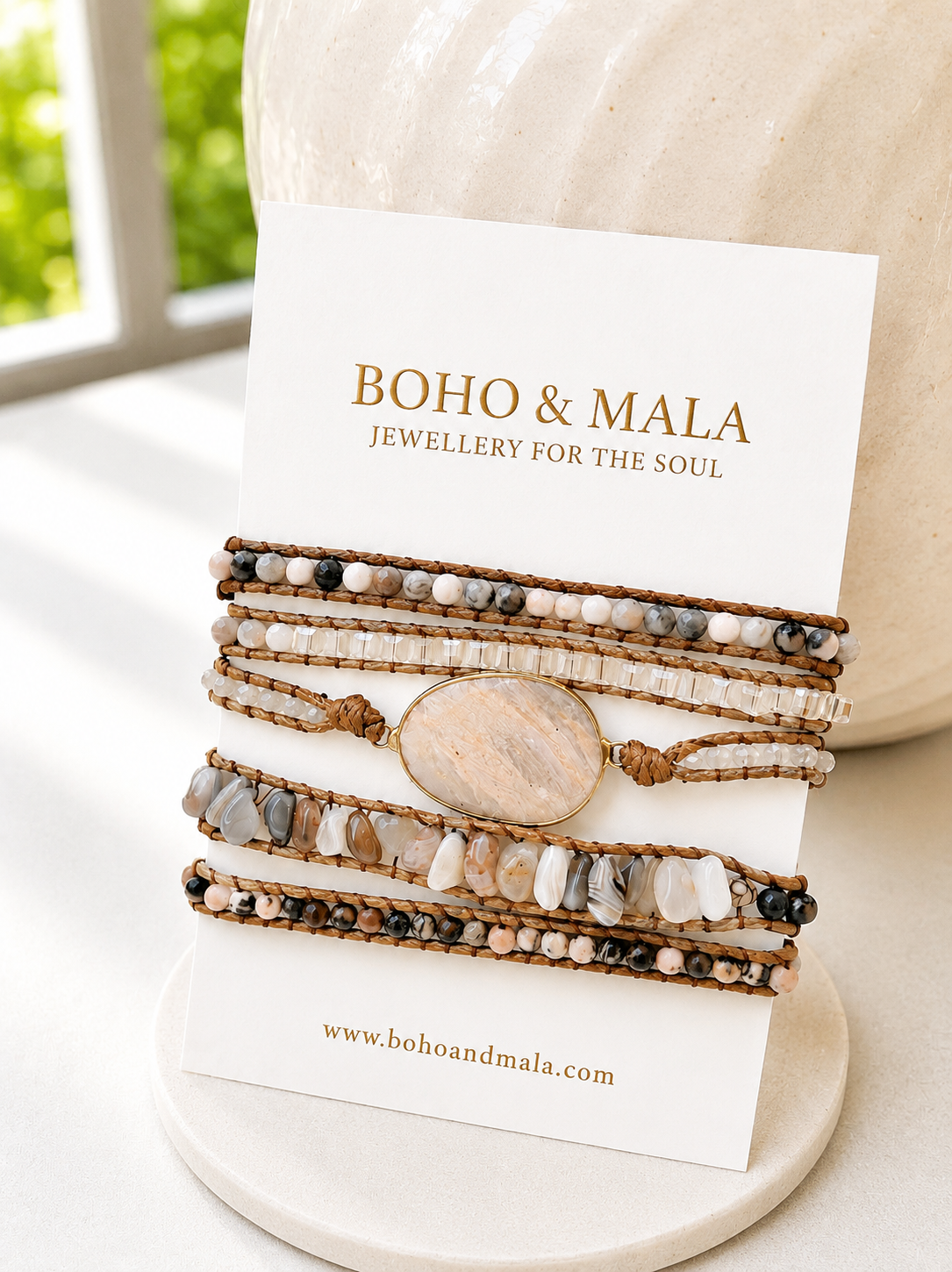 
                  
                    Blush agate wrap bracelets with a central stone on a 'Boho & Mala' branded card.
                  
                