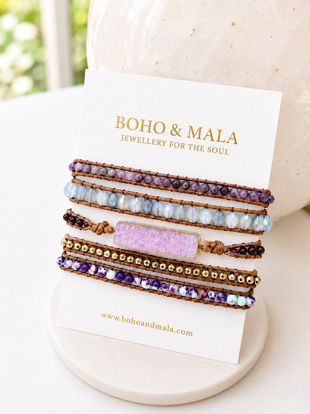 
                  
                    Set of beaded pink druzy wrap bracelets on a white card with 'Boho & Mala' branding.
                  
                