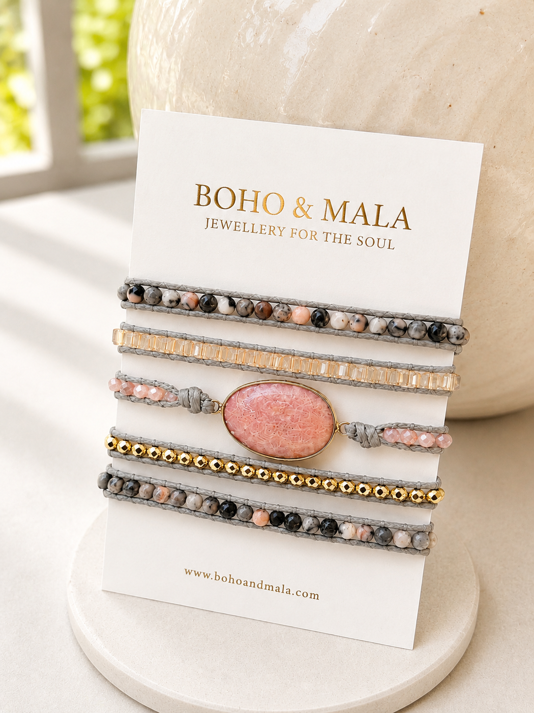 
                  
                    Set of pink rhodonite bracelets on a card with 'Boho & Mala' branding, displayed on a white surface.
                  
                