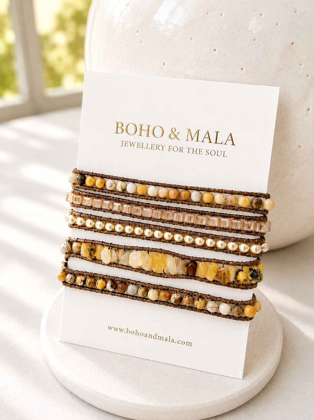 
                  
                    Stack of beaded yellow jade wrap bracelets on a display card with 'Boho & Mala' branding.
                  
                