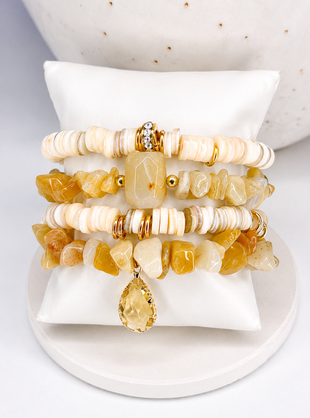 
                  
                    Set of beaded natural stone bracelets with yellow stones on a white stand
                  
                
