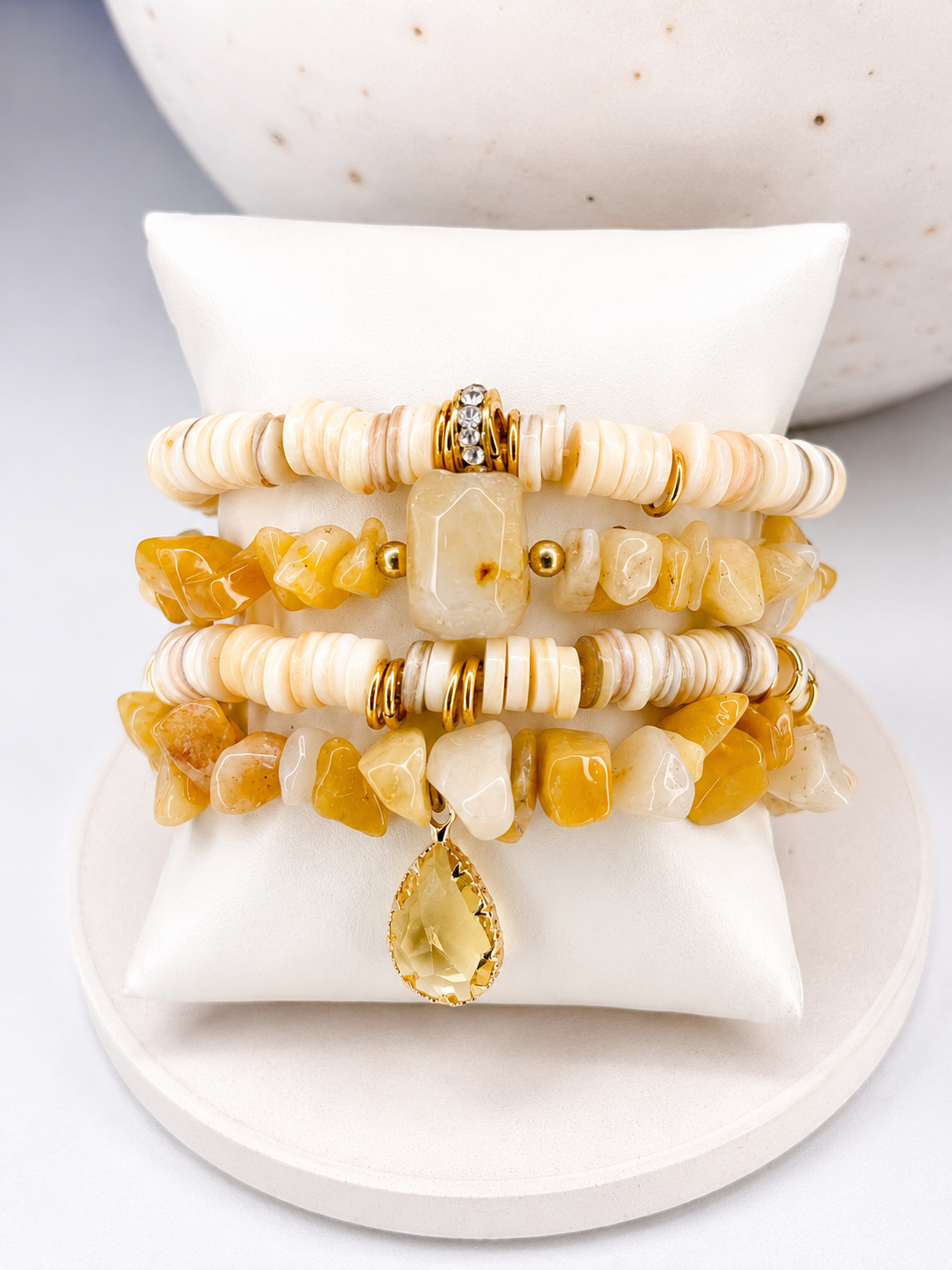 
                  
                    Stack of beaded natural honey stone bracelets on a white surface with a neutral background
                  
                