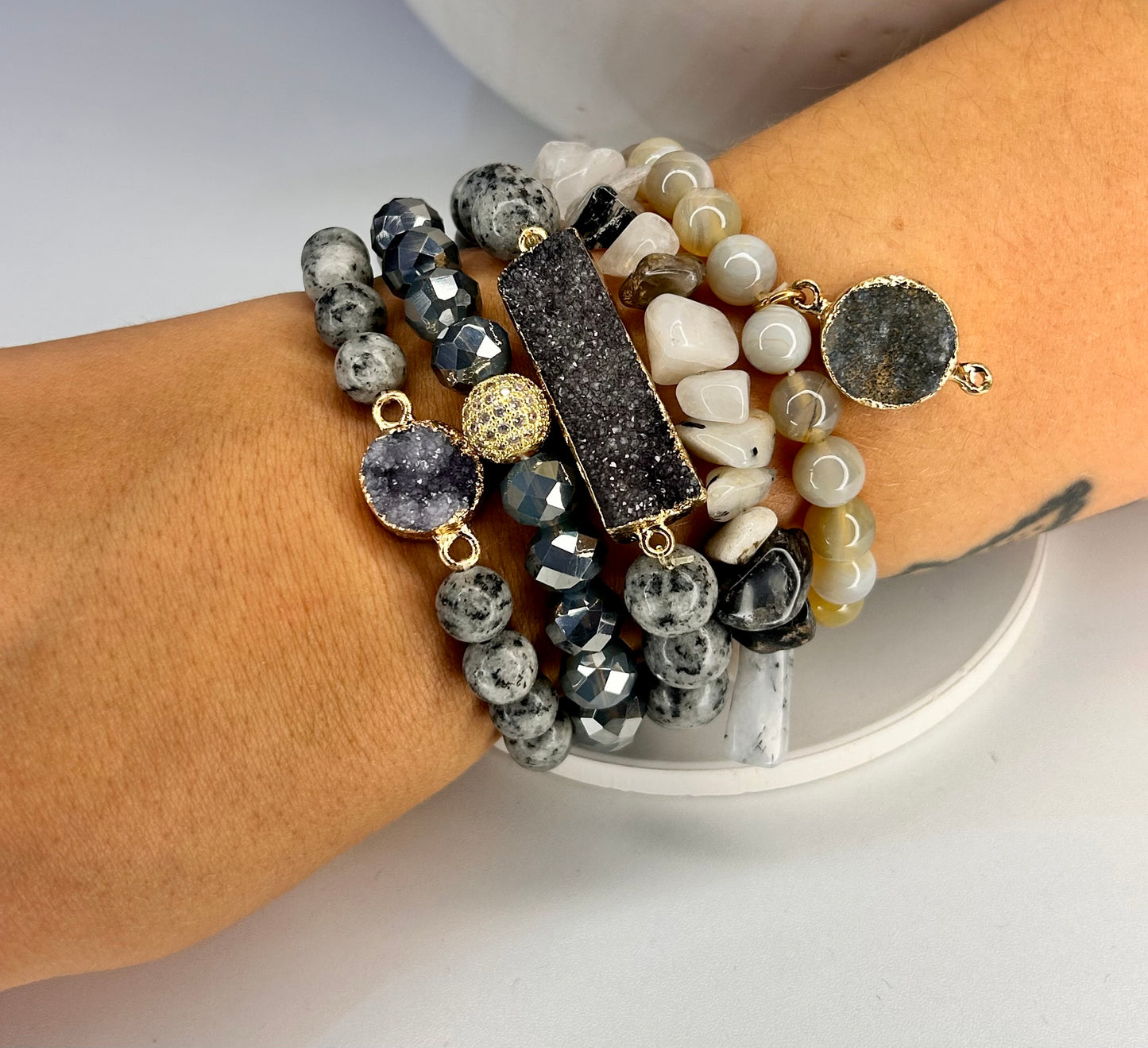 
                  
                    Stack of beaded bracelets on a wrist with a neutral background with real natural druzy stones
                  
                