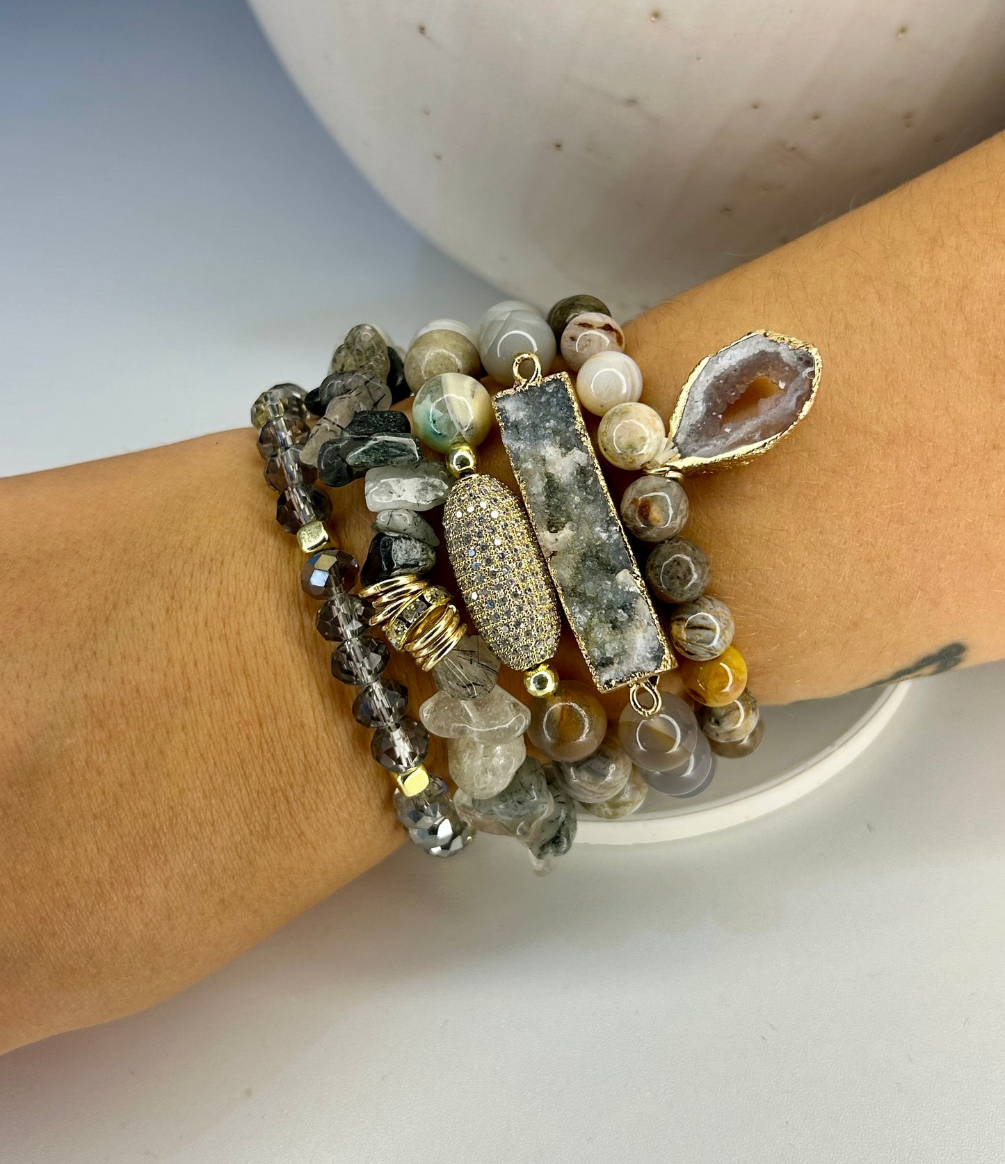 
                  
                    Stack of beaded moonstone bracelets on a wrist with a neutral background
                  
                