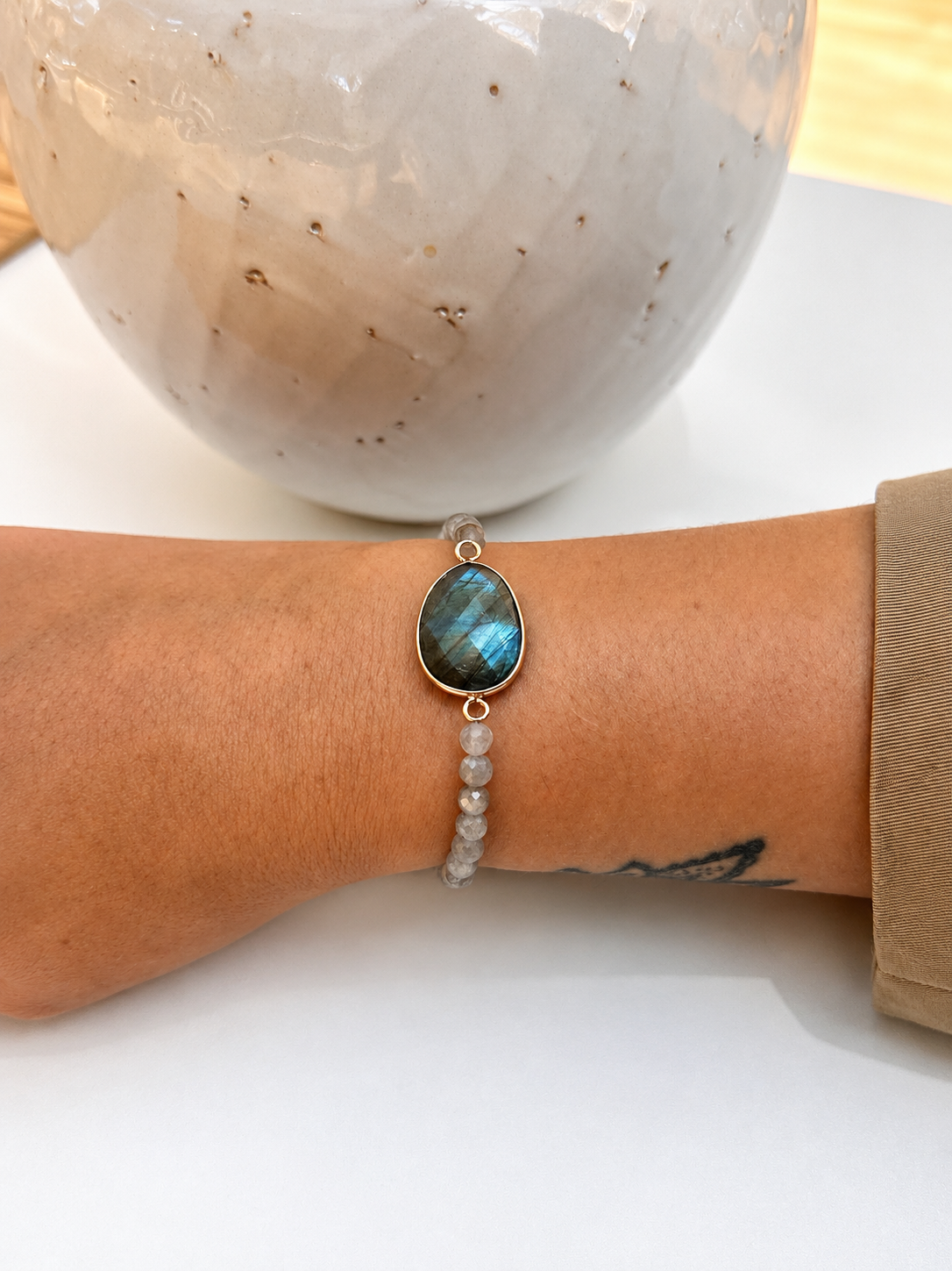 
                  
                    Faceted Labradorite beaded bracelet featuring a large natural Labradorite centre stone in a gold-plated setting, displayed on models wrist
                  
                