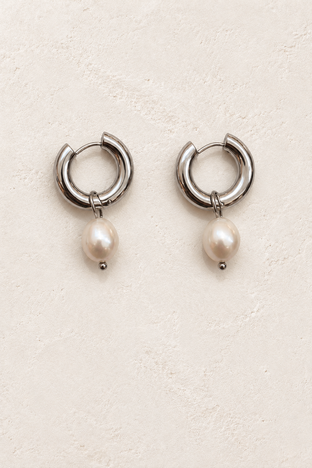 
                  
                    Alondra Silver Pearl Drop Hoop Earrings on warm ivory plaster
                  
                