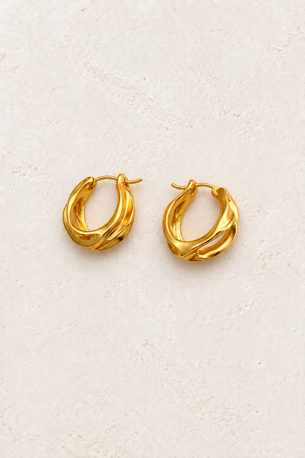 
                  
                    Alora Sculpted Wave Hoops on warm ivory textured background
                  
                