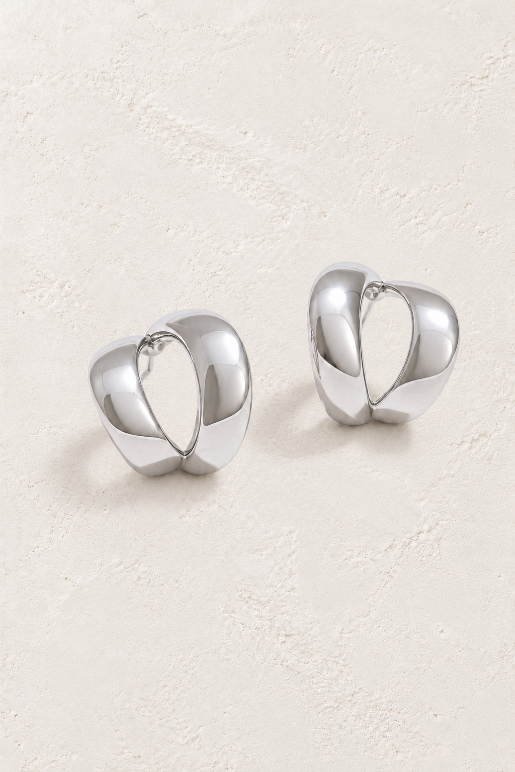 
                  
                    Silver sculptural teardrop hoops on approved cream hero background
                  
                
