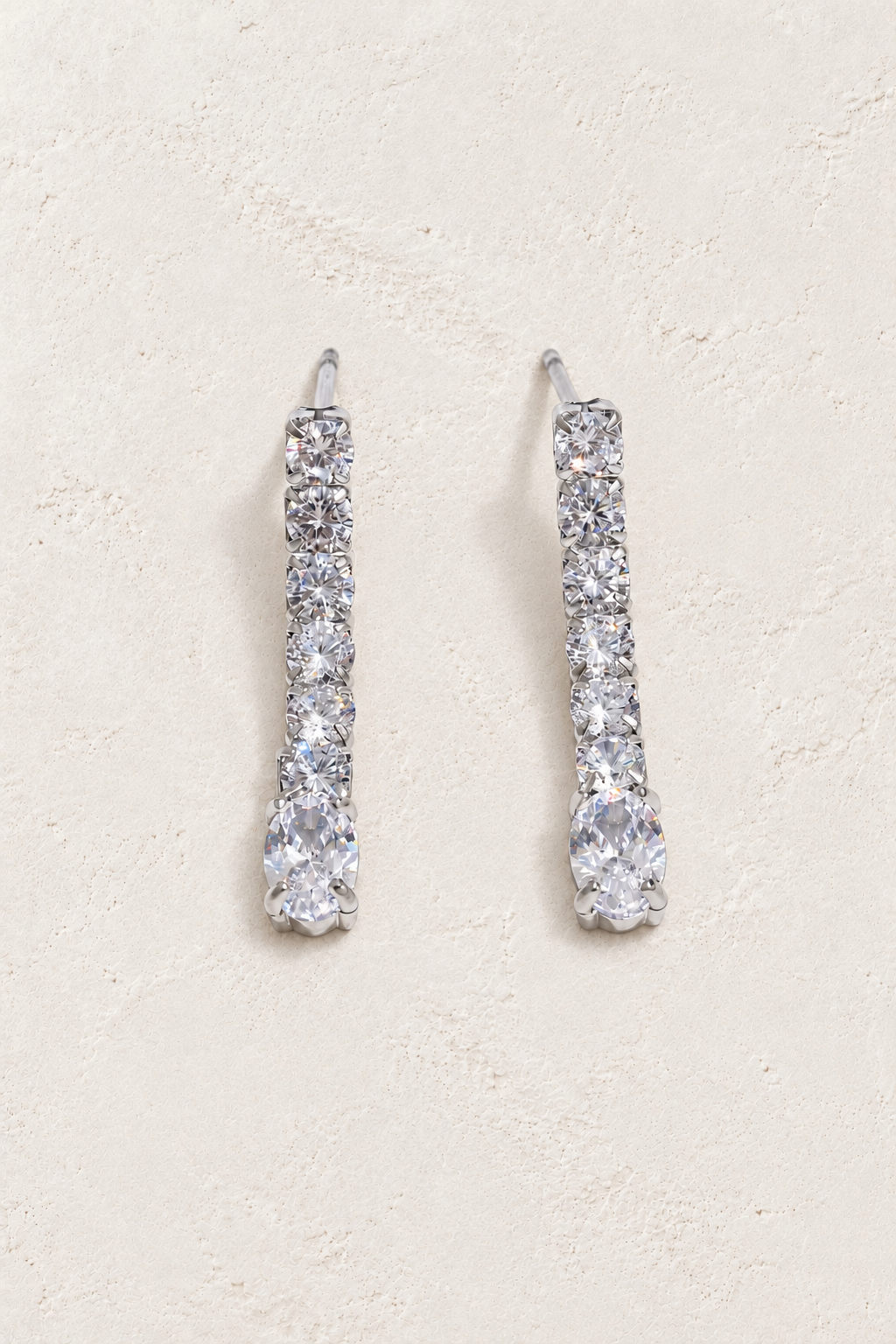 
                  
                    Silver crystal line and oval drop earrings on approved cream hero background
                  
                