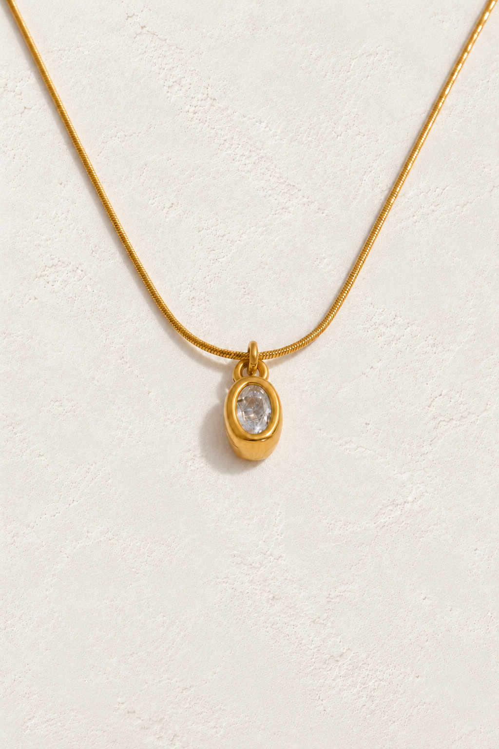 
                  
                    Gold oval bezel cubic zirconia necklace on approved cream hero background
                  
                