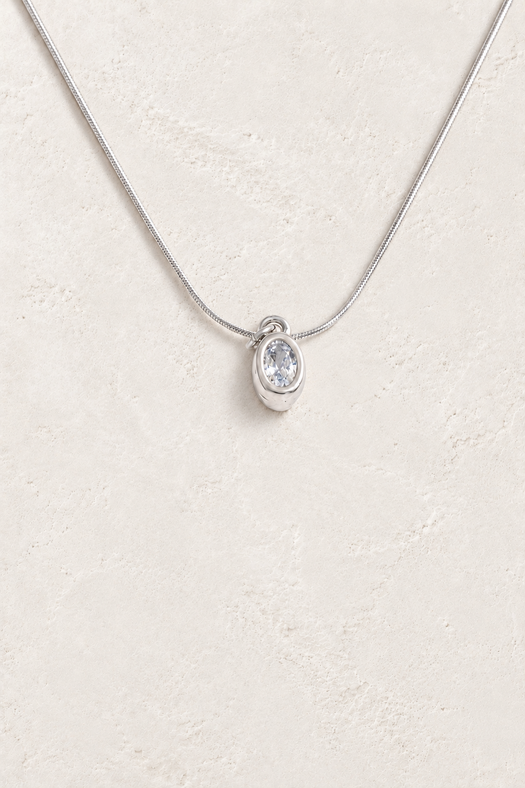 
                  
                    Silver oval bezel cubic zirconia necklace on approved cream hero background
                  
                