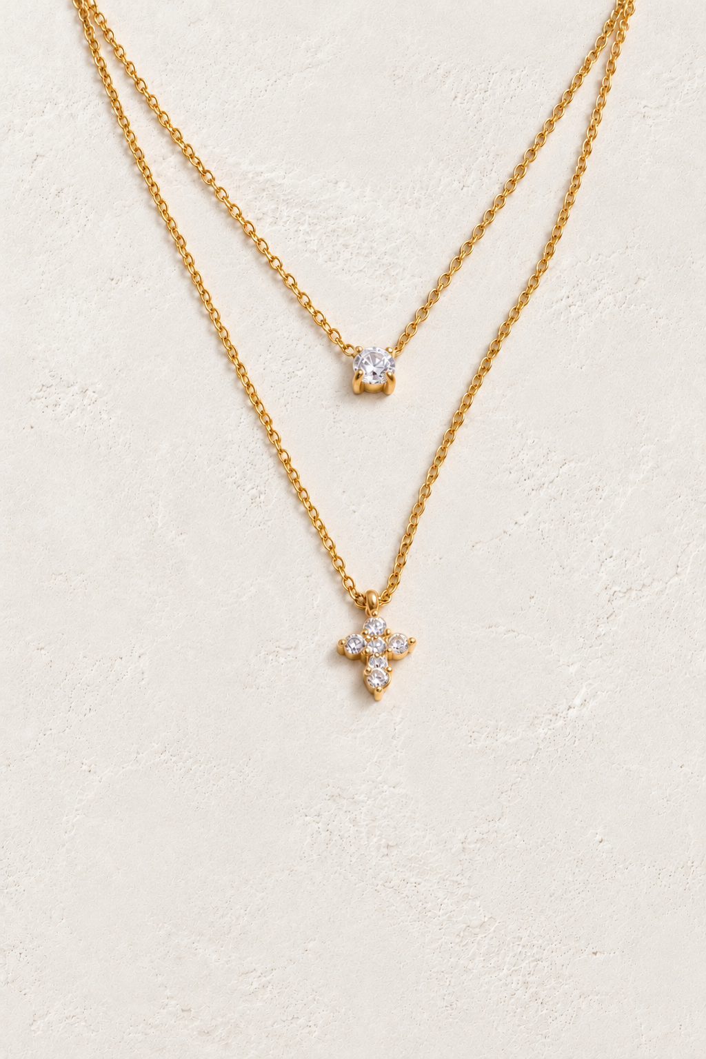 
                  
                    Gold layered solitaire and cross necklace on approved cream hero background
                  
                