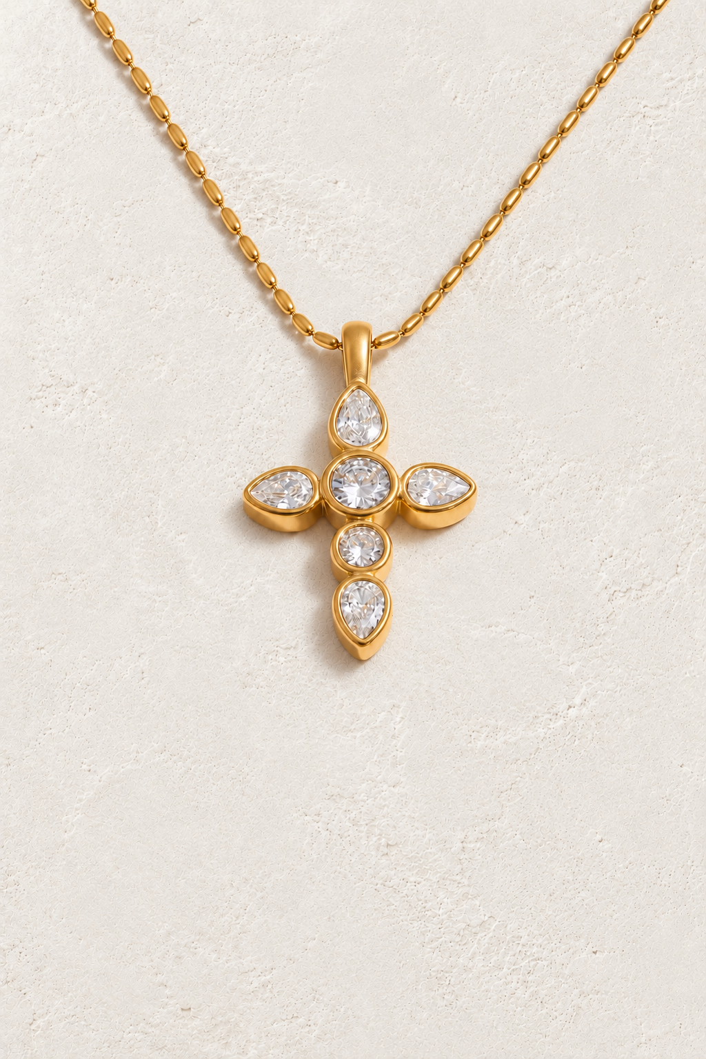 
                  
                    Gold bezel set cross necklace on approved cream hero background
                  
                