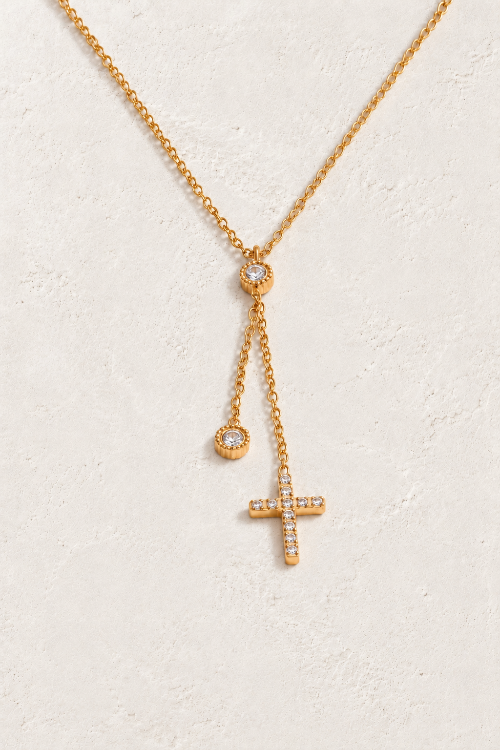 
                  
                    Gold crystal cross drop necklace on approved cream hero background
                  
                