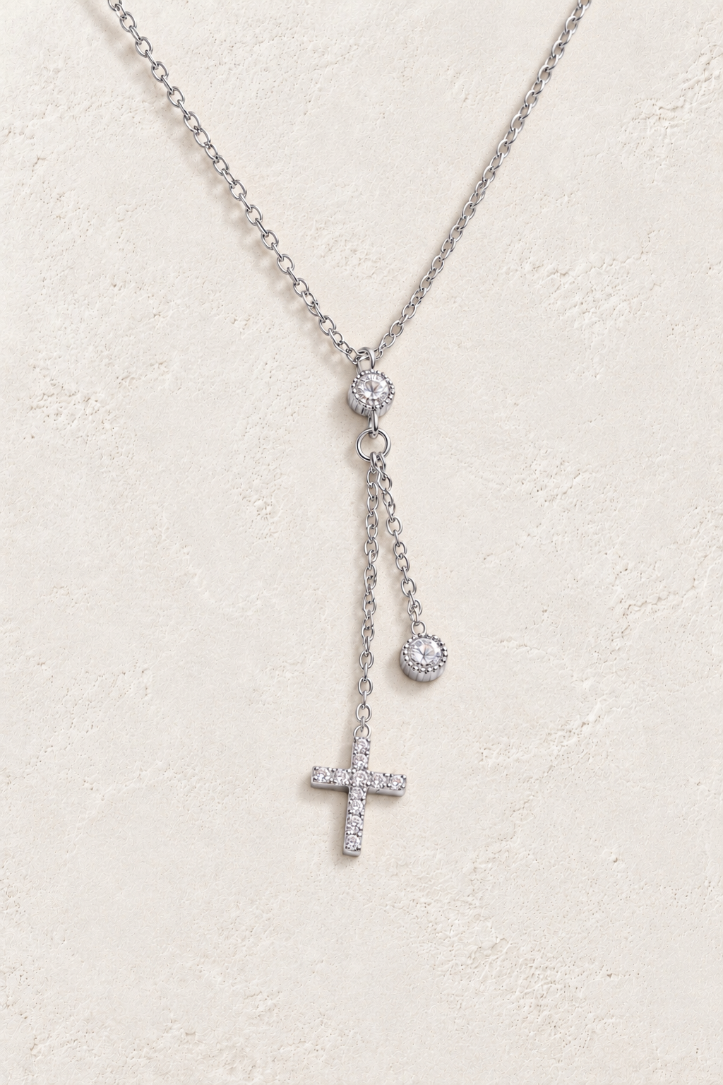 
                  
                    Silver crystal cross drop necklace on approved cream hero background
                  
                