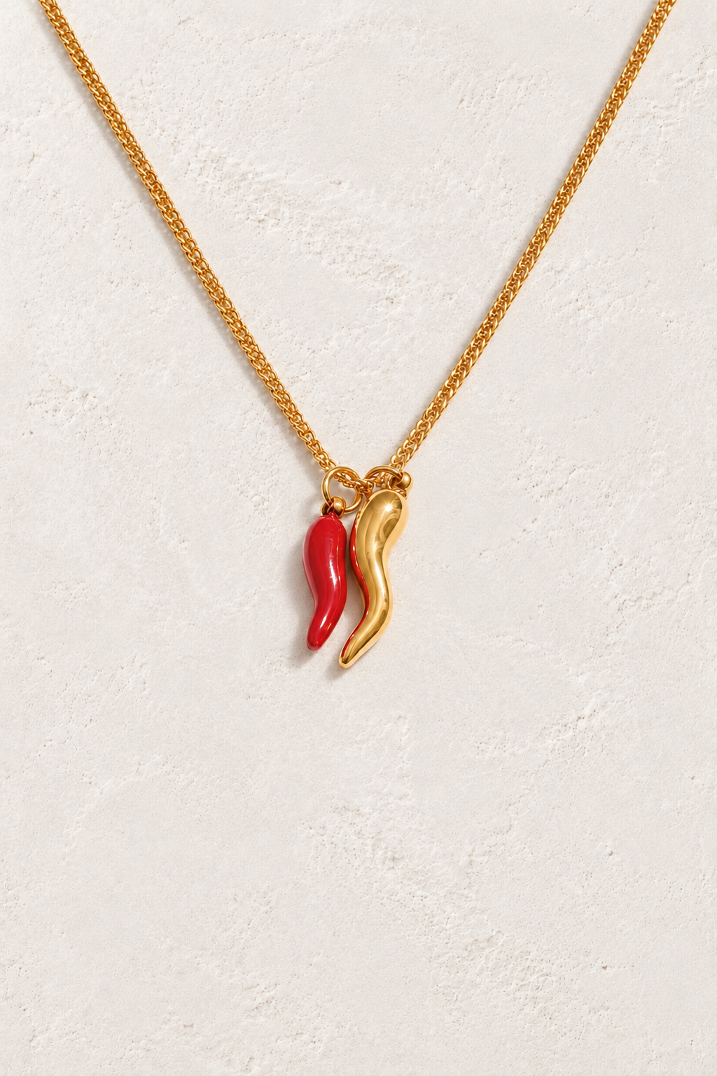 
                  
                    Gold and red double chilli necklace on approved cream hero background
                  
                