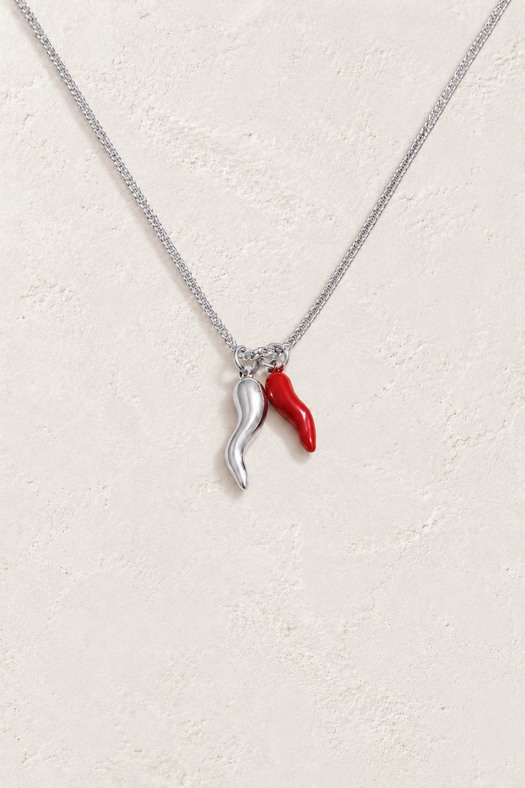 
                  
                    Silver and red double chilli necklace on approved cream hero background
                  
                