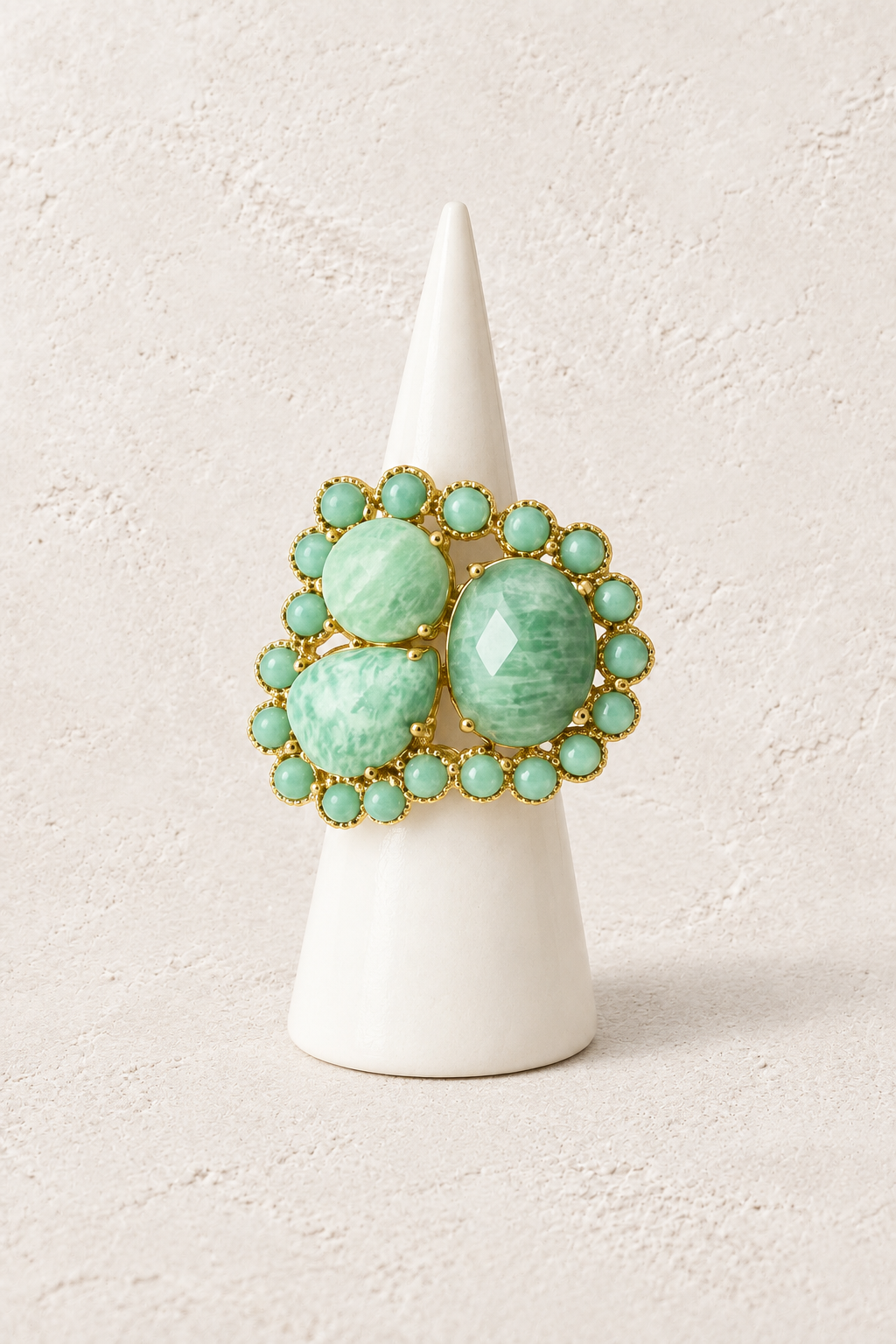 Aurelia Amazonite Halo Ring on a white display cone against a warm textured background