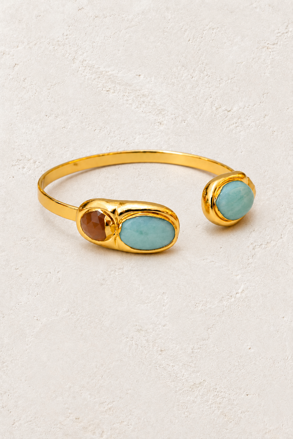 Aurelia gold cuff with amazonite and sunstone on a warm off-white textured plaster background