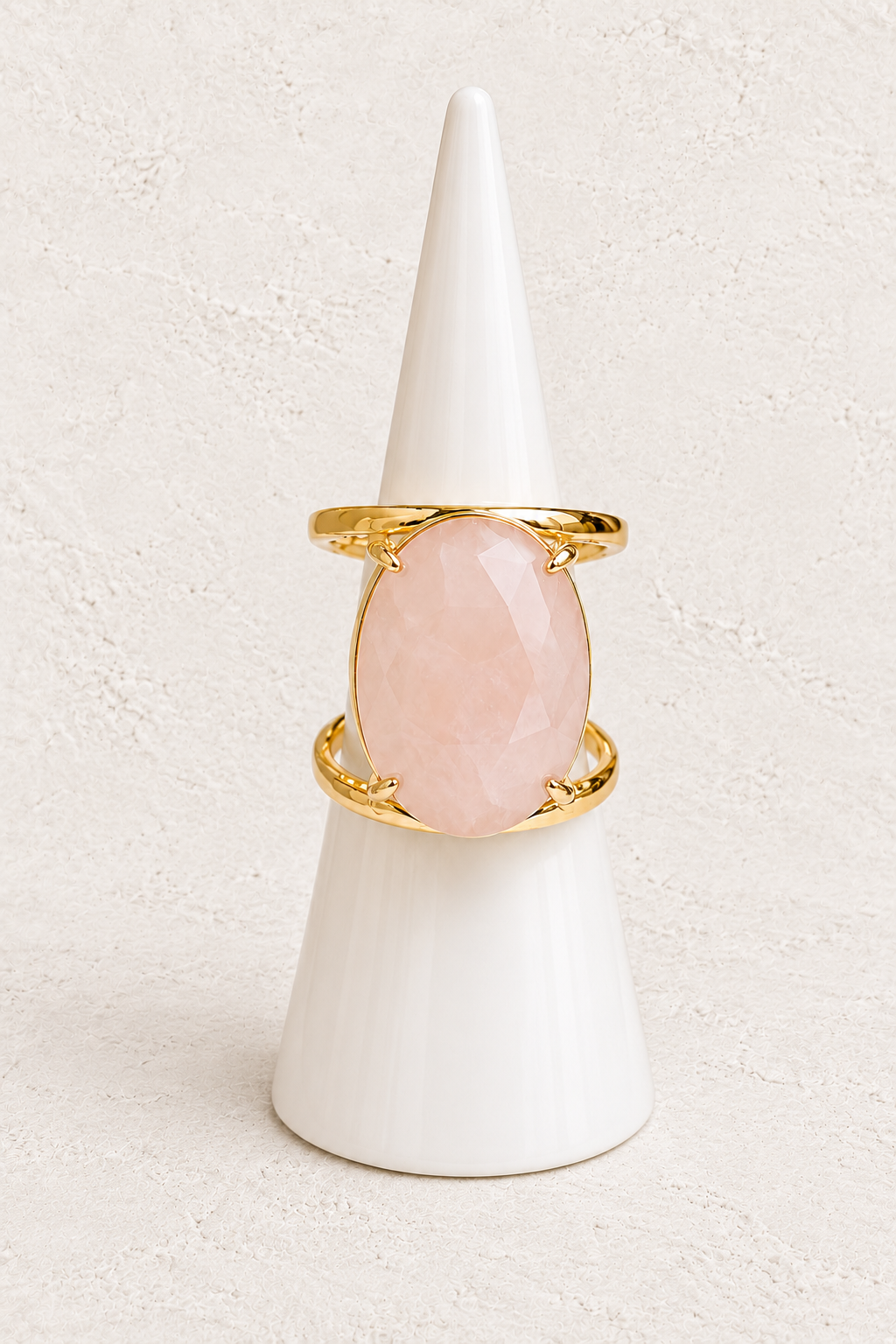 Aurevia Rose Quartz Statement Ring on white cone against warm textured background