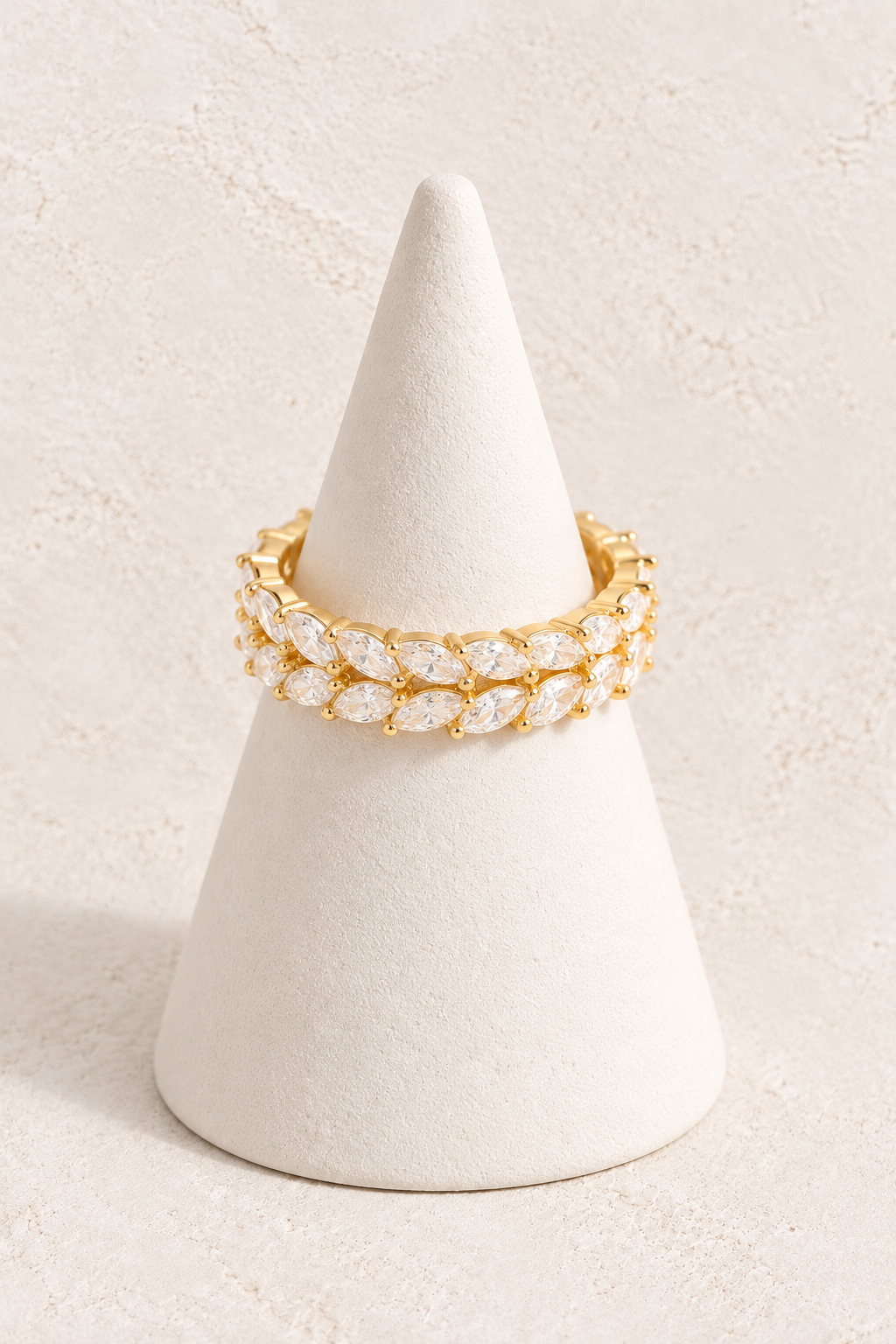 Aurora Bloom Ring on a white display cone against a warm textured background
