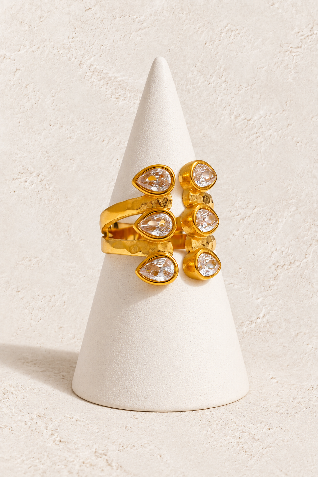 Aurora Luxe Ring on a white display cone against a warm textured background