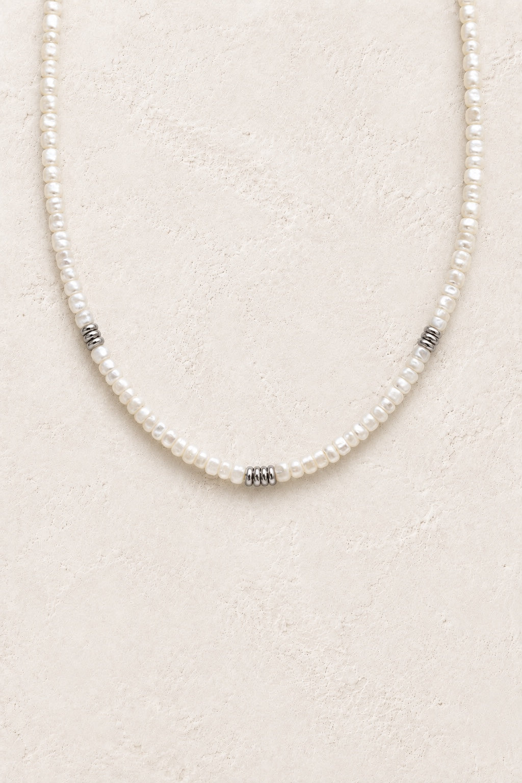 Avelisse pearl strand waterproof necklace with silver-tone spacers on a neutral background