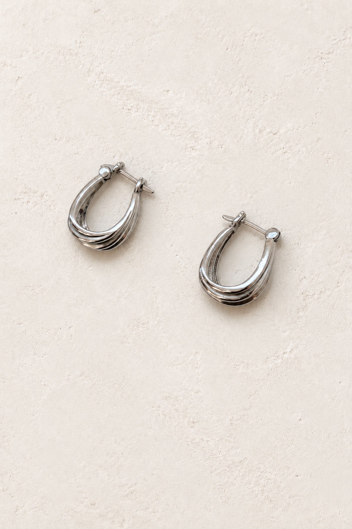 
                  
                    Avora silver sculpted teardrop hoop earrings on ivory plaster
                  
                
