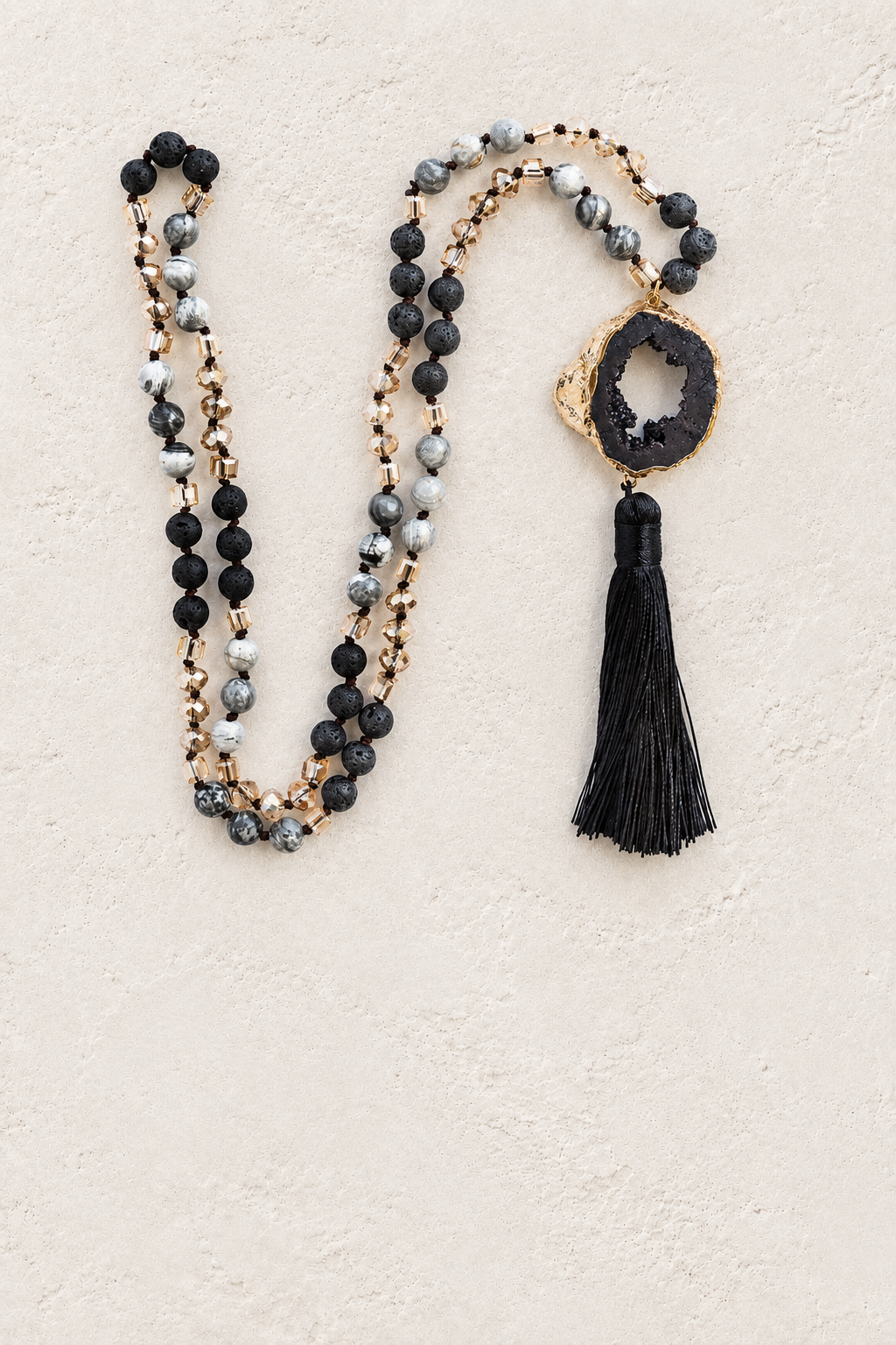 
                  
                    Black Agate Slice Tassel Necklace on warm ivory plaster background
                  
                