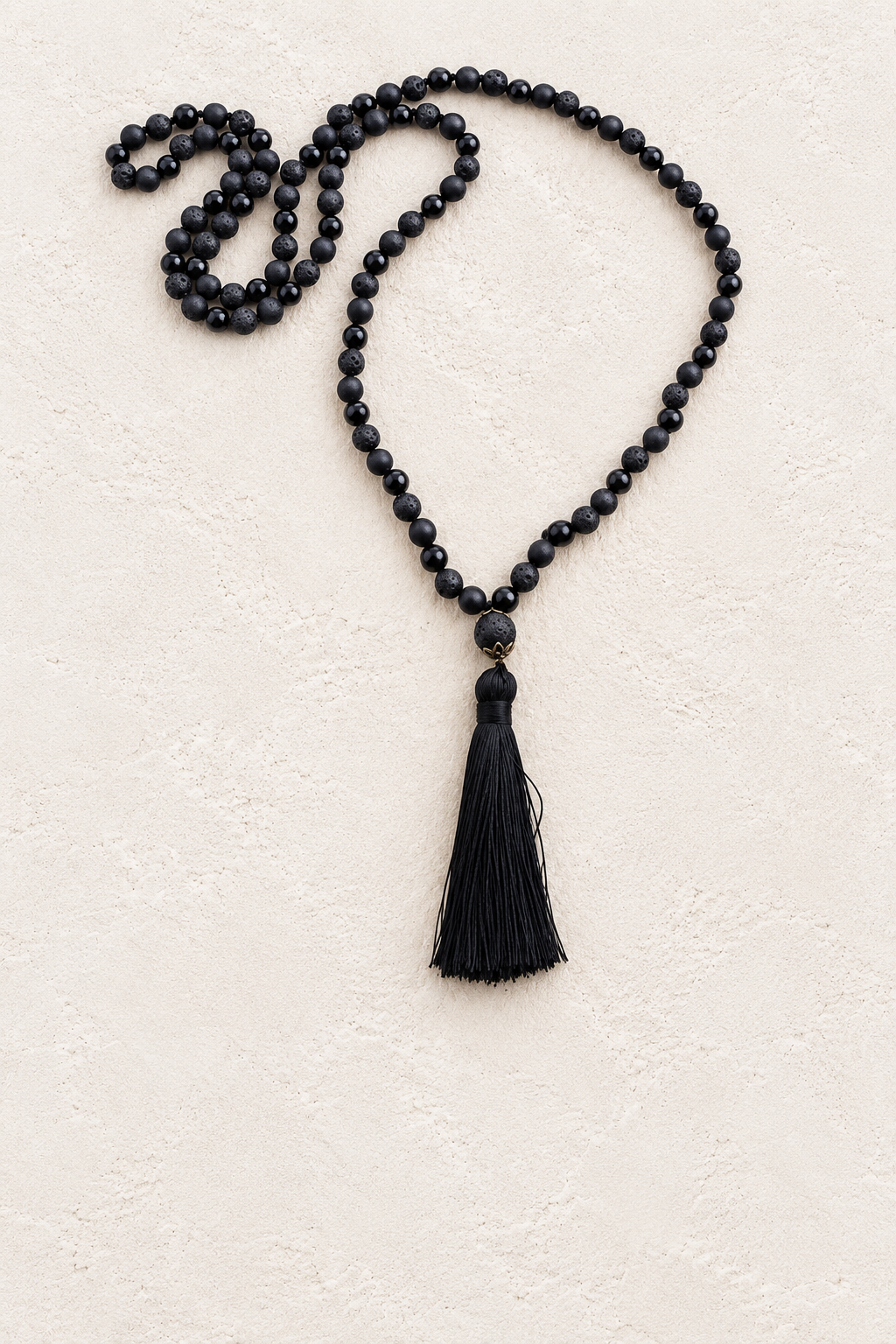 Black Tassel Mala Necklace on warm cream plaster background
