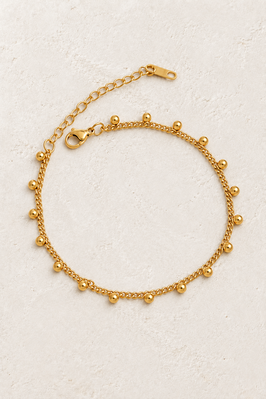 
                  
                    Gold Dangle Bead Bracelet on ivory stone
                  
                