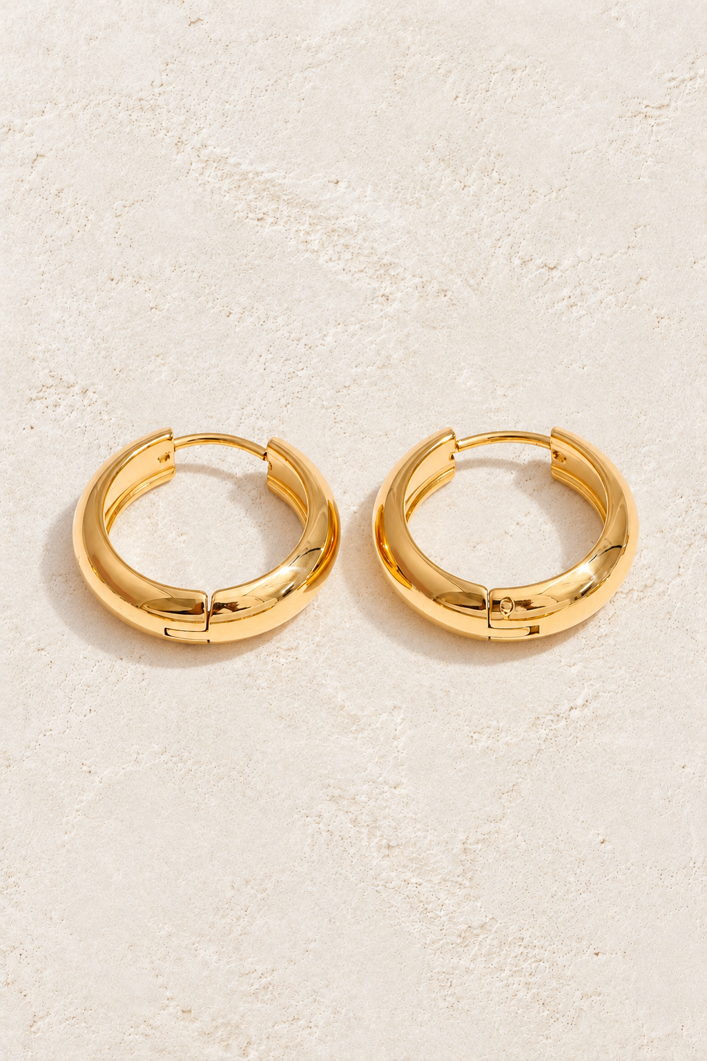 
                  
                    Classic gold waterproof hoop earrings — 14 mm on approved cream background
                  
                