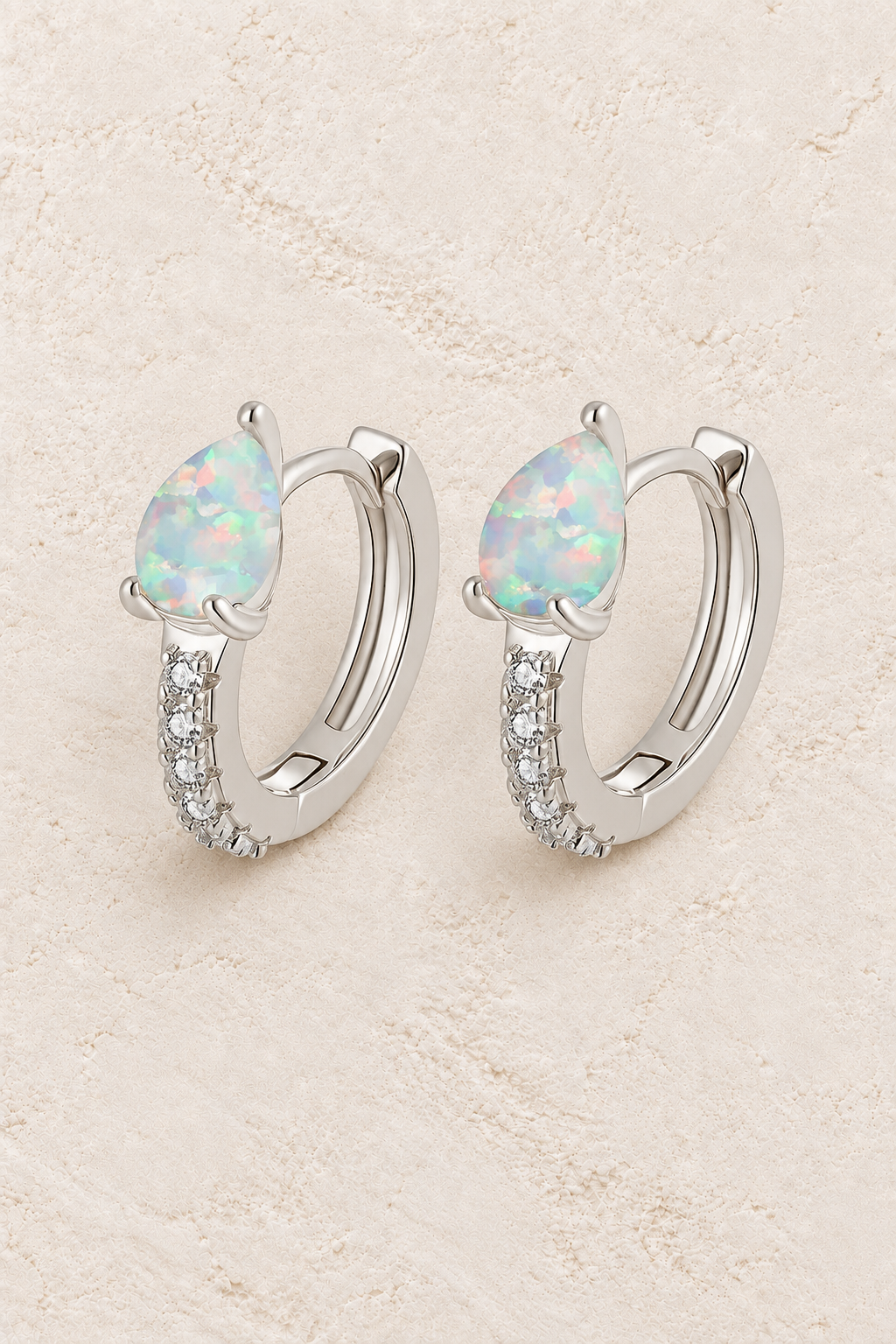 Boho & Mala Opal Huggies Sterling Silver Hoop Earrings on warm cream textured background