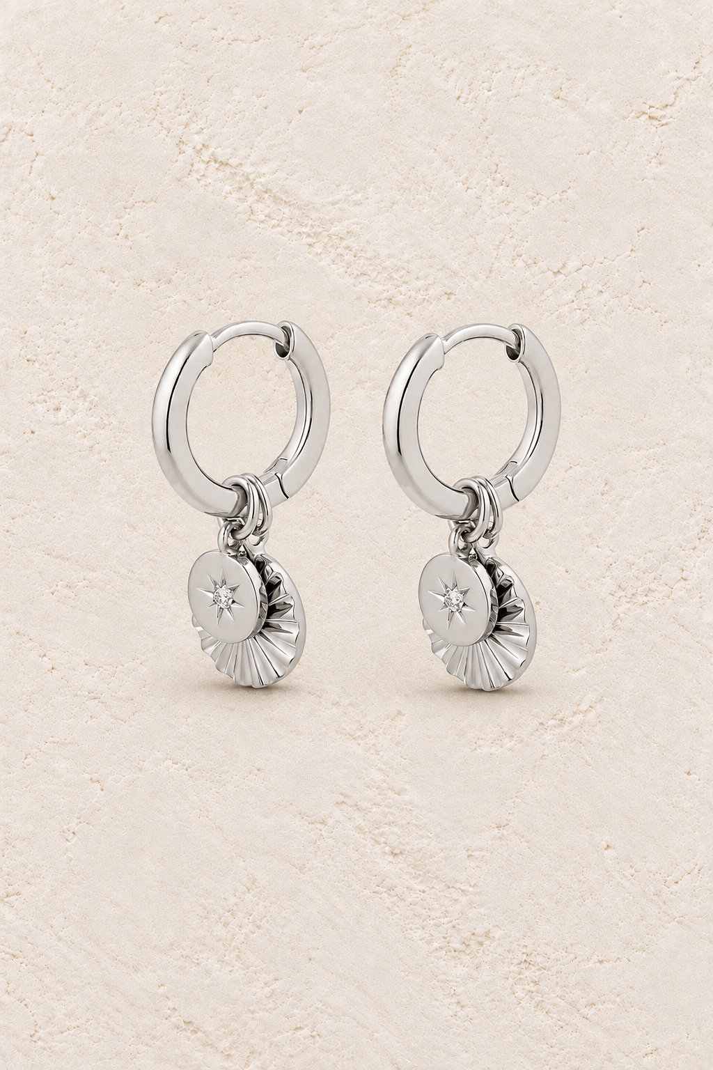 
                  
                    Boho & Mala Round Stars Huggies Sterling Silver Hoop Earrings on warm cream textured background
                  
                