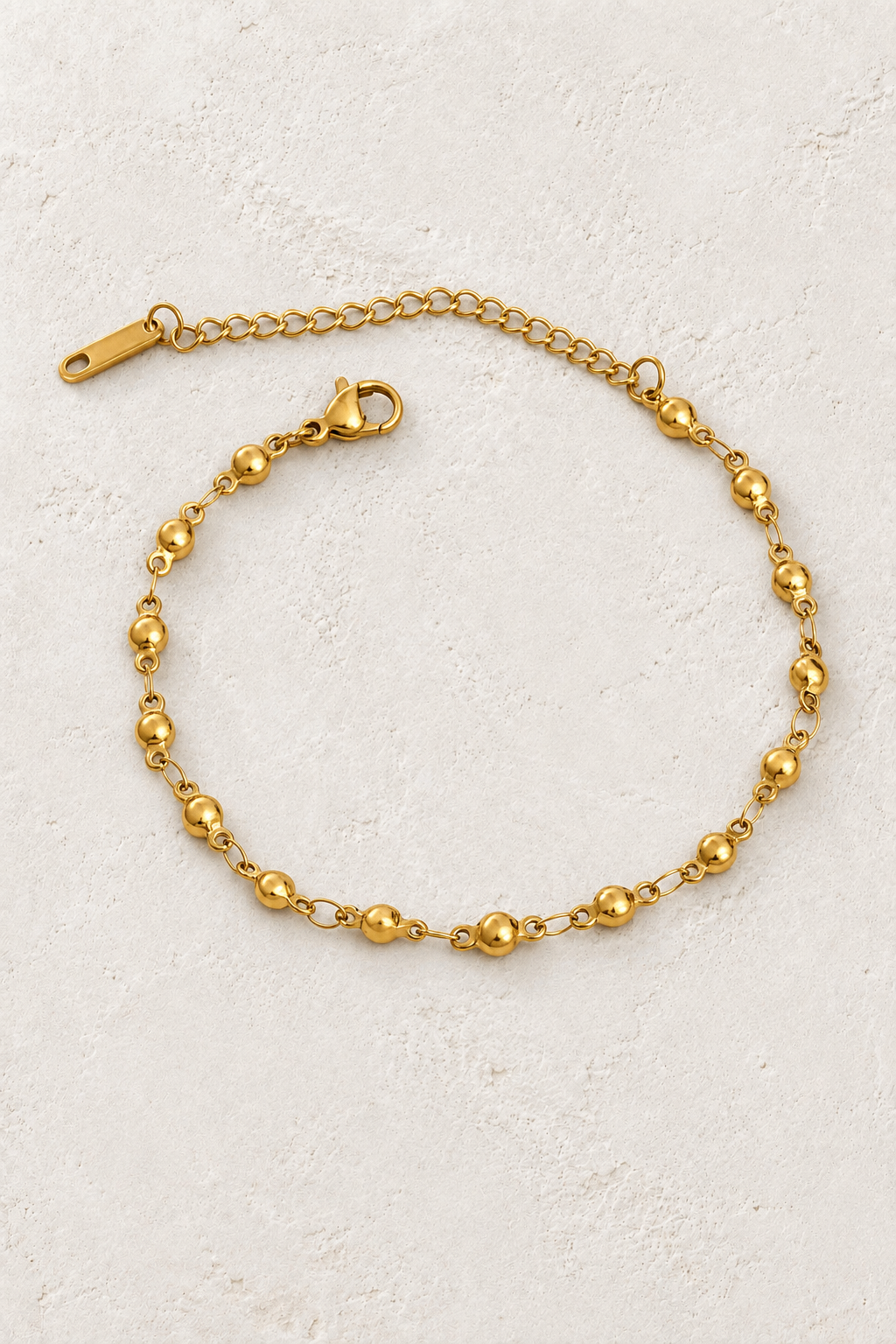 
                  
                    Gold Spaced Bead Bracelet on ivory stone
                  
                