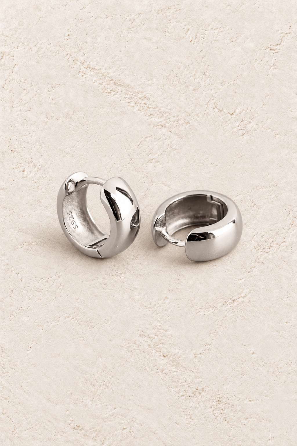 
                  
                    Boho & Mala Sterling Silver Hoop Huggie Earrings on warm cream textured background
                  
                