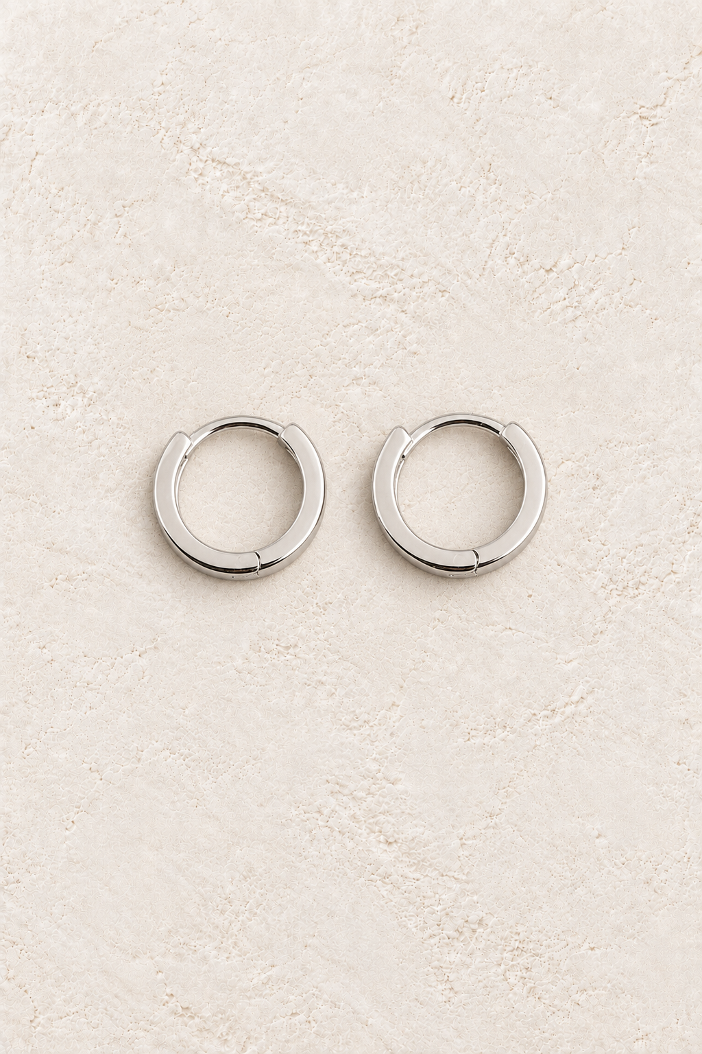 Boho & Mala Sterling Silver Hoop Huggie Earrings on warm cream textured background